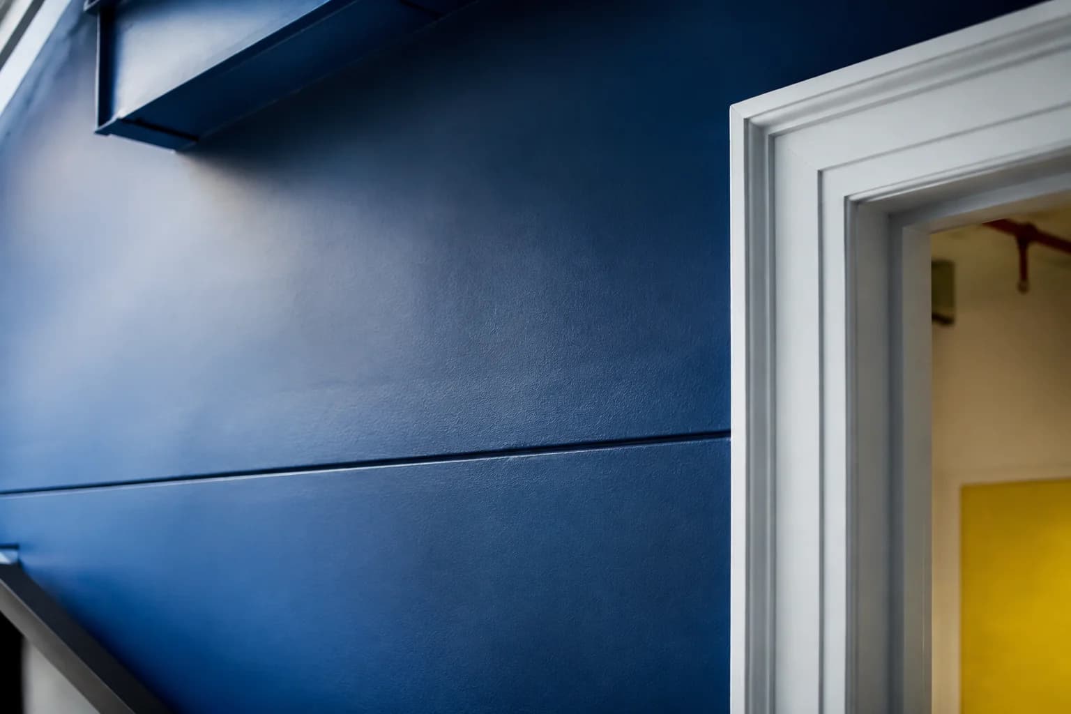 Close view of a blue painted wall and white door trim